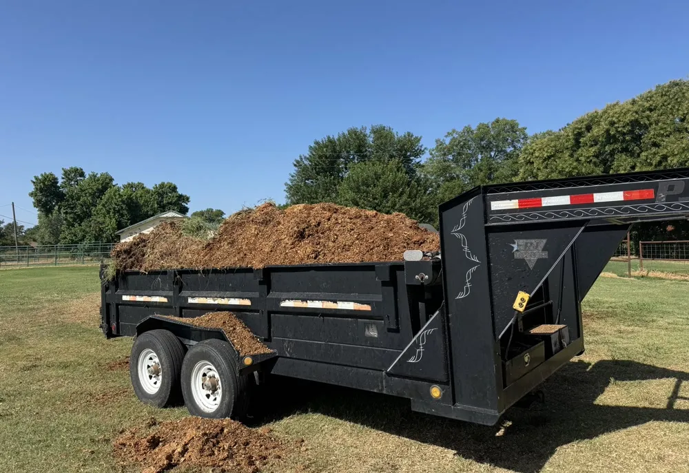 Gooseneck dump trailer loaded with cleared brush