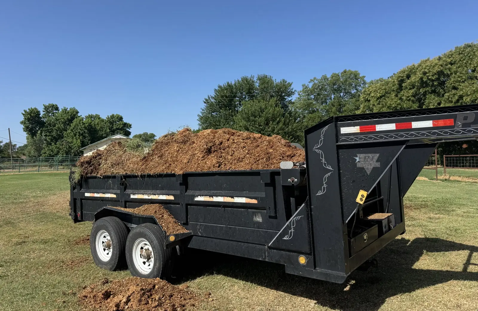 Double AA Land Services gooseneck dump trailer loaded with cleared brush