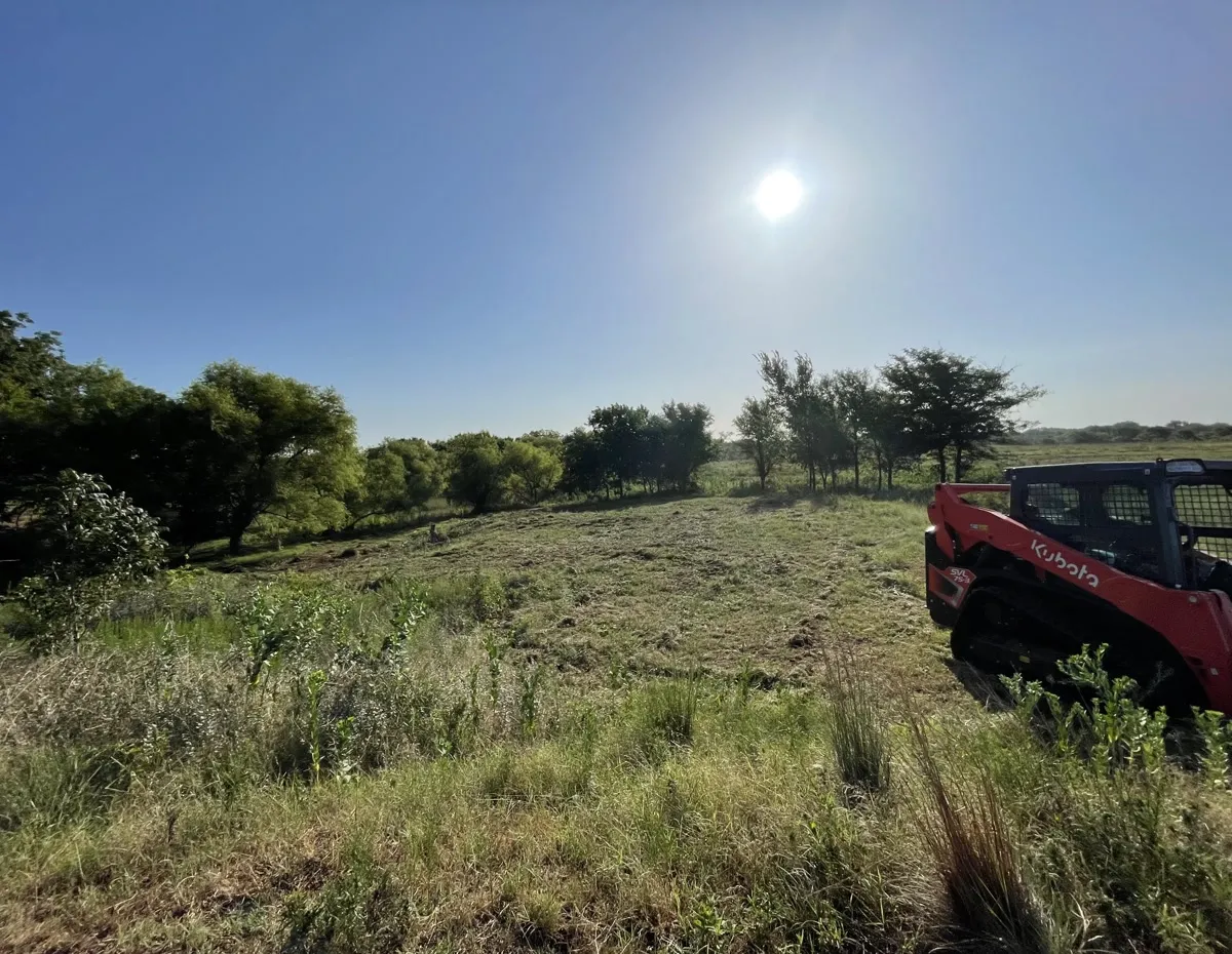 Double AA track skid steer on freshly mowed Oklahoma pasture